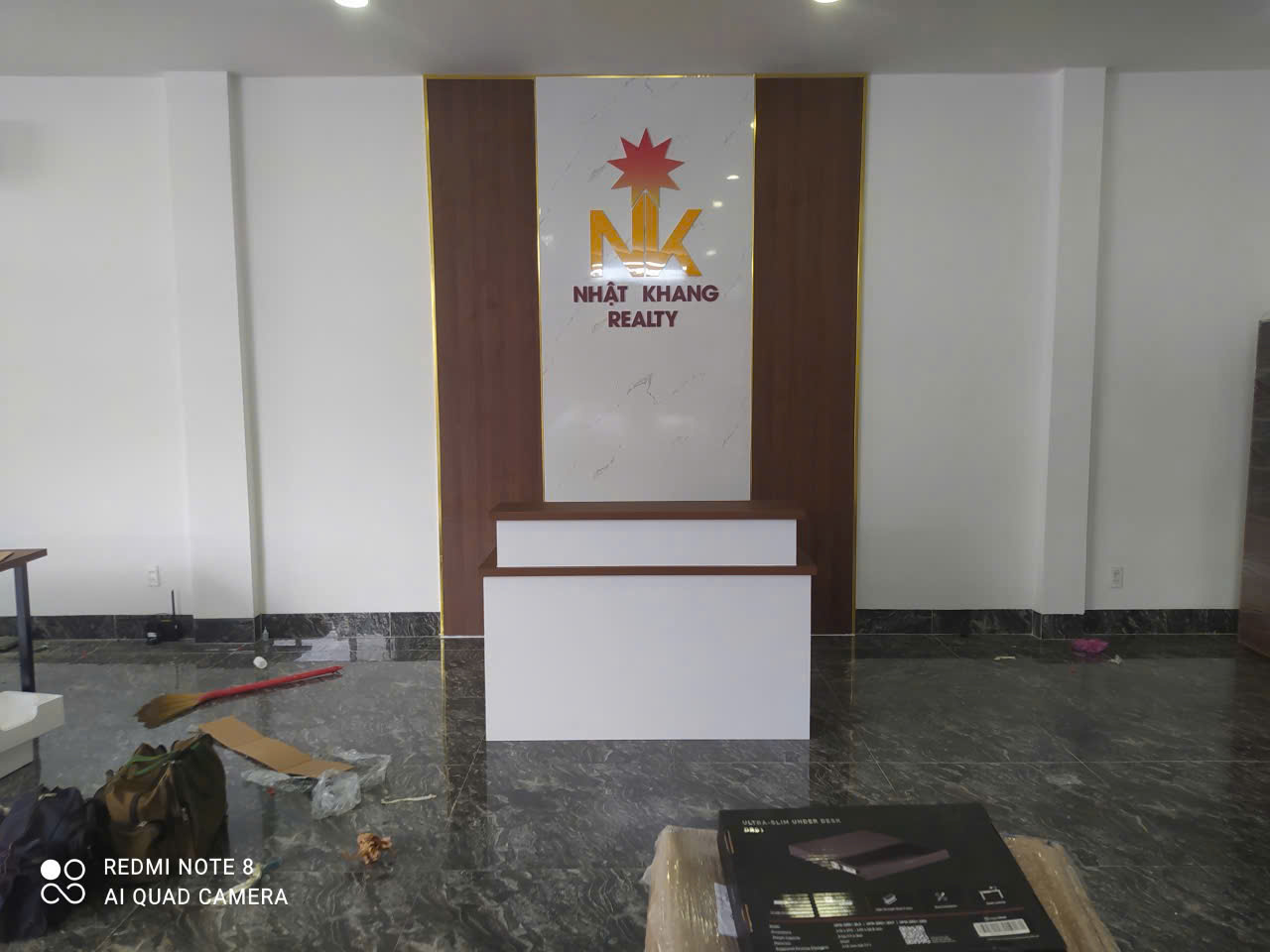 Thi công backdrop quầy lễ tân logo Inox gương Nhật Khang Realty Nha Trang